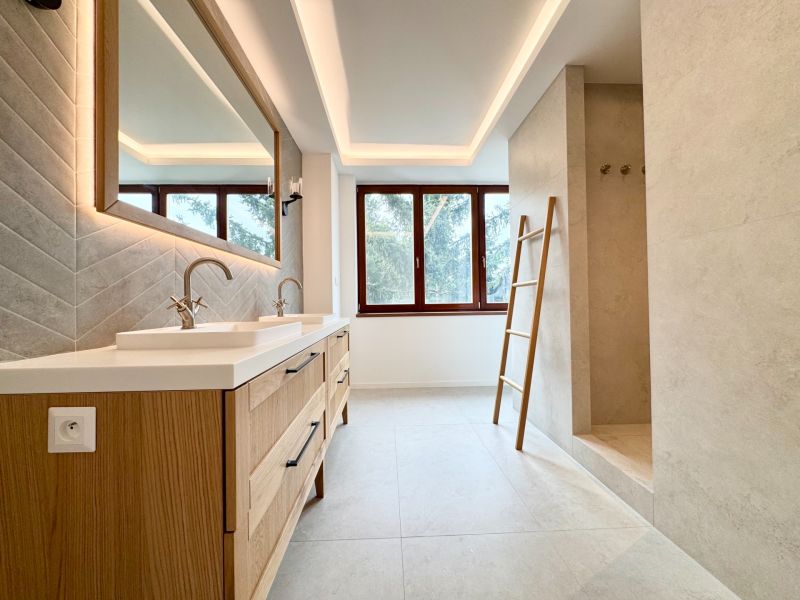 A bathroom in a 3-room apartment with a double sink and a large window.