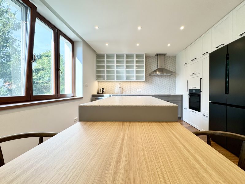 A kitchen in a 3-room apartment with an island and LED lighting, flooring with a wooden decor.