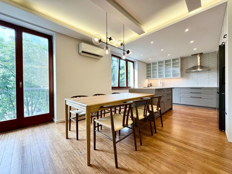 Kitchen in a 3-room apartment, wooden decor flooring, large windows, dining table.