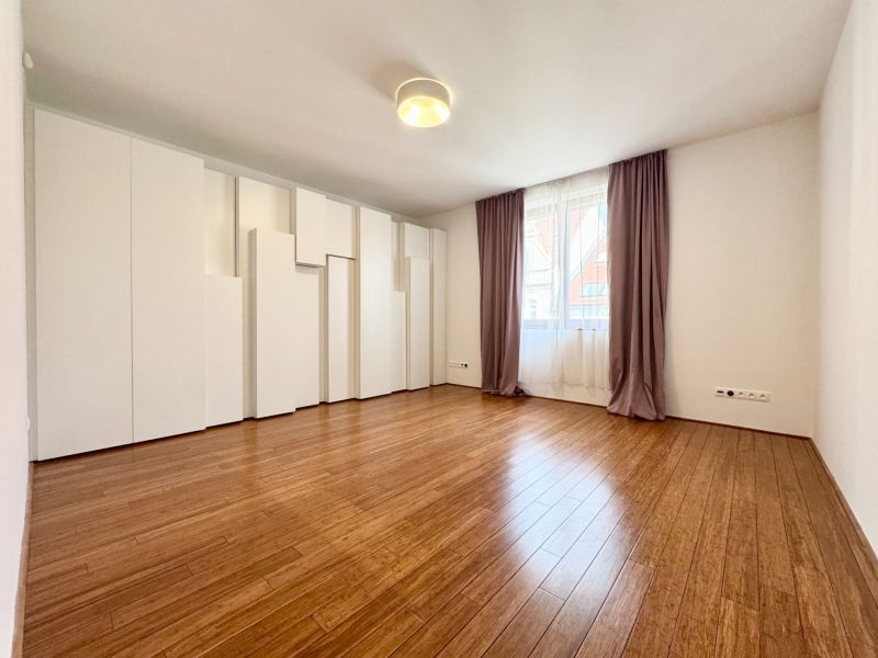 A spacious room in a 3-room apartment with wood-patterned flooring and built-in wardrobes.
