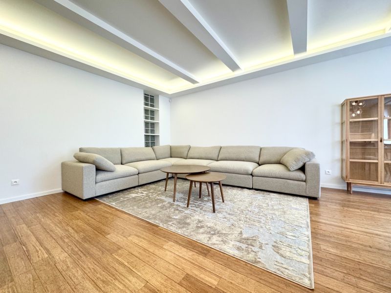 Living room in a 3-room apartment with a sofa, carpet on the floor with a wooden decor.