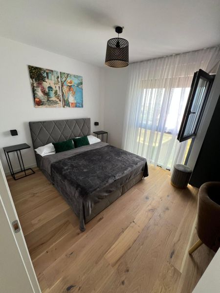A bedroom with a bed, an art painting, and a wooden decor floor in a 3-room apartment.