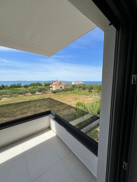 A balcony with a view of greenery and the sea in a 3-room apartment in Privlaka.