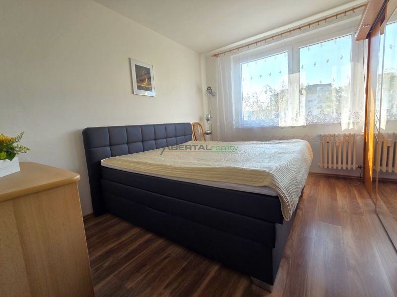 Bedroom with a large bed, wooden decor flooring, and a window in a 3-room apartment.