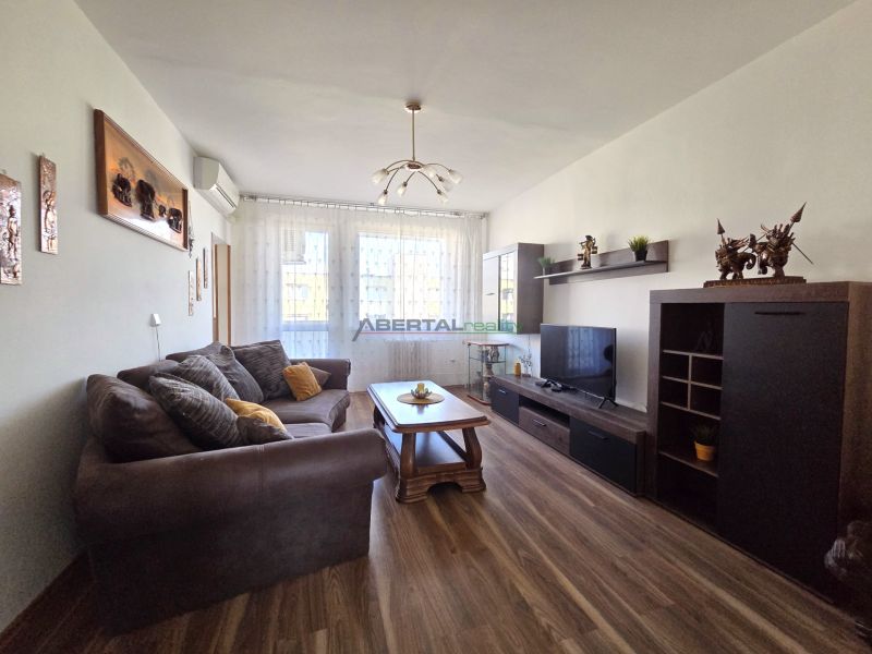 Living room in a three-room apartment with a sofa and a wooden decor floor.