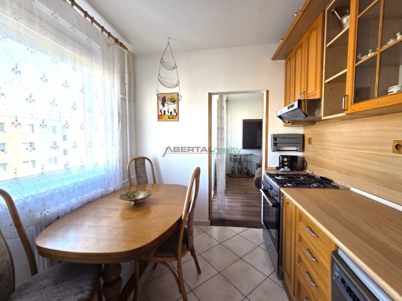 A kitchen in a 3-room apartment with a dining table, tiles, and wooden decor.