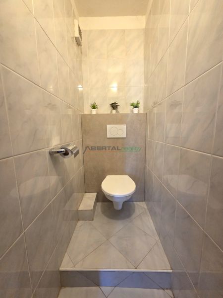 A bathroom with tiles in a 3-room apartment, complemented by decorative plants.