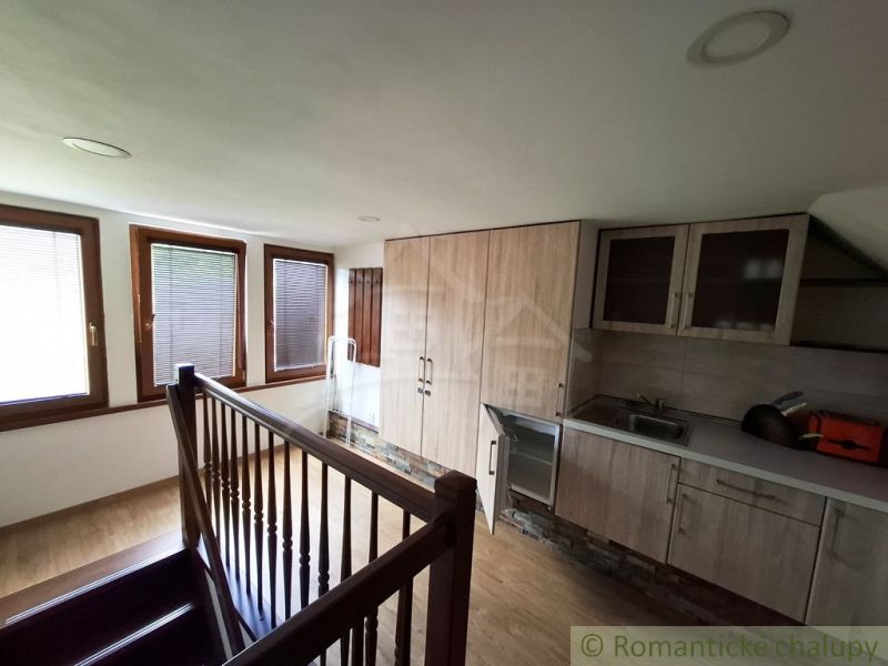A kitchen with a wood-patterned floor and stairs in commercial premises.