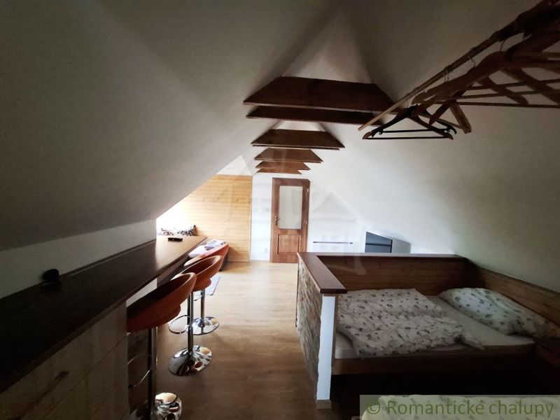 Loft space with a bed, bar counter, and wooden decor flooring.