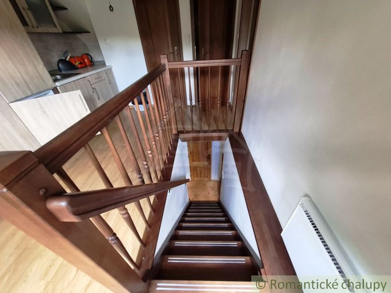 Interior with a wooden staircase next to the kitchen counter and a floor with a wooden decor.