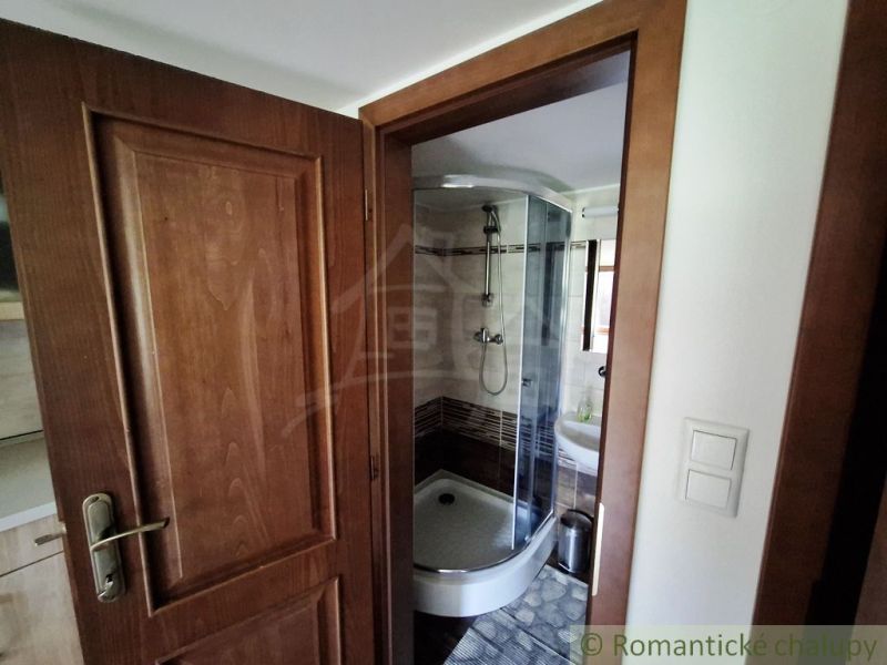 Bathroom with a corner shower and rustic wooden doors in commercial premises.