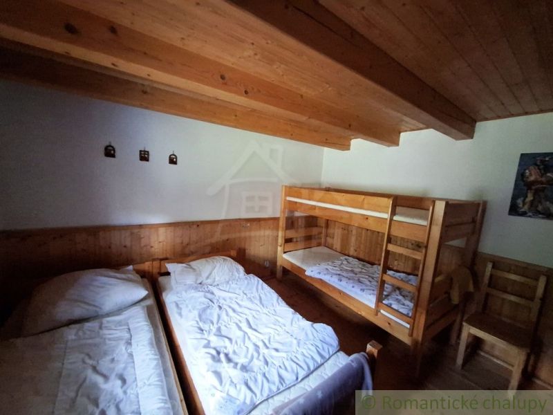 A room with two beds and a bunk bed, wooden decor on the walls and ceiling.