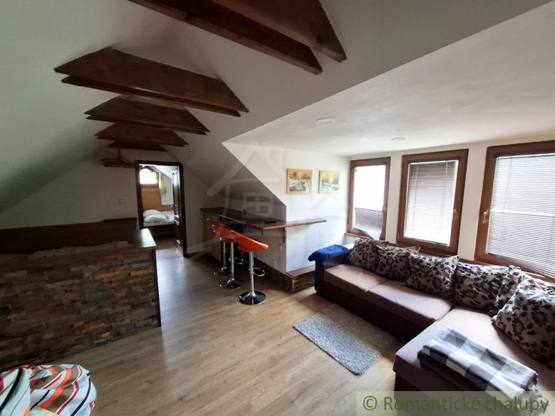 Attic interior with wood-decor flooring, a sofa set, and a bar counter.