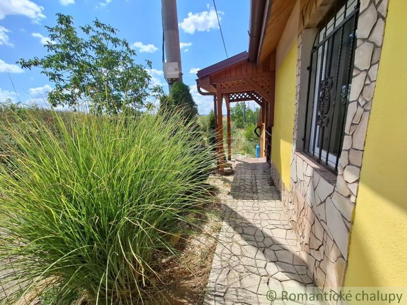 Cottage in Gbelce, stone path, terrace, grass, and wooden details.