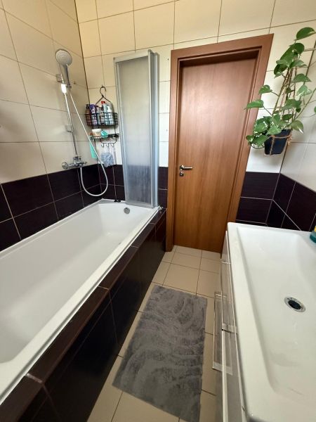 A bathroom in a 3-room apartment with a bathtub, sink, and tiles, suitable for comfort.