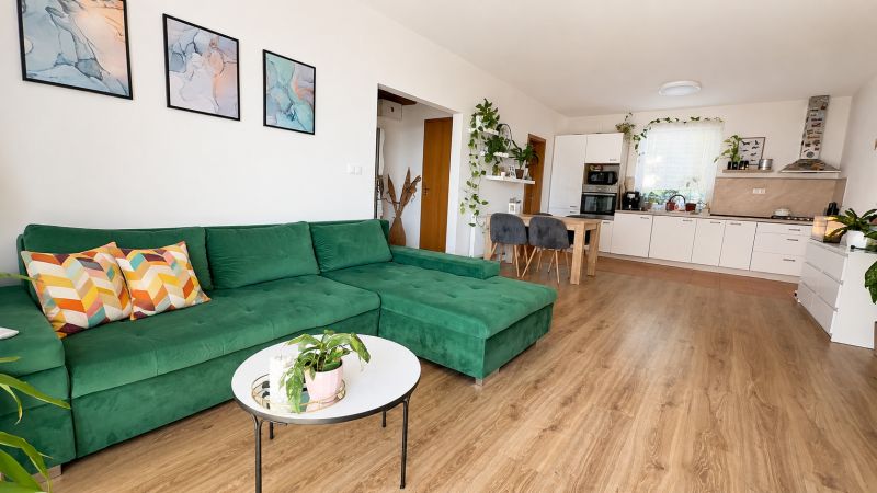 Living room in a 3-room apartment with a comfortable green sofa and a wooden decor floor.