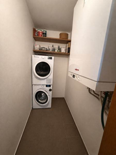 Laundry room in a 3-room apartment with a washing machine, dryer, shelves, and a gas boiler.