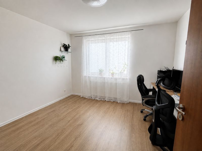 A room in a 3-room apartment with a wooden decor floor and a desk.