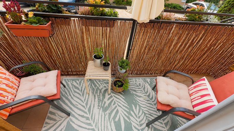 A balcony with flowers and chairs with cushions in a 3-room apartment.