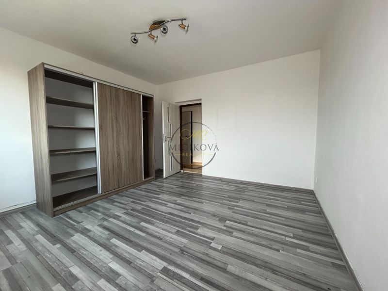 Spacious room with wood-patterned flooring and a built-in wardrobe in a 2-room apartment.