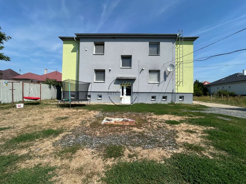 A two-story building in Telince with a yard, a trampoline, and a swing.
