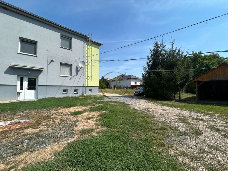 Exterior in Telince with parking near a two-story building and a shelter.