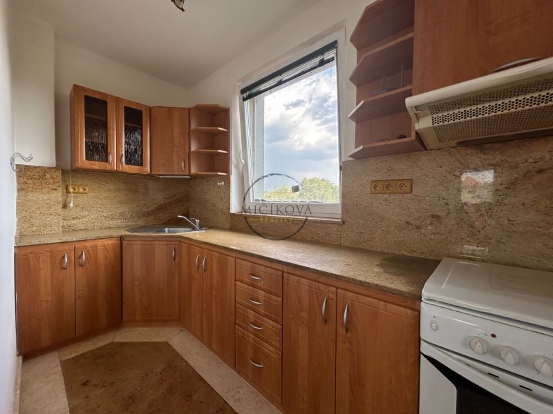 A kitchen with wooden decor, kitchen cabinets, appliances, and a window in a two-room apartment.
