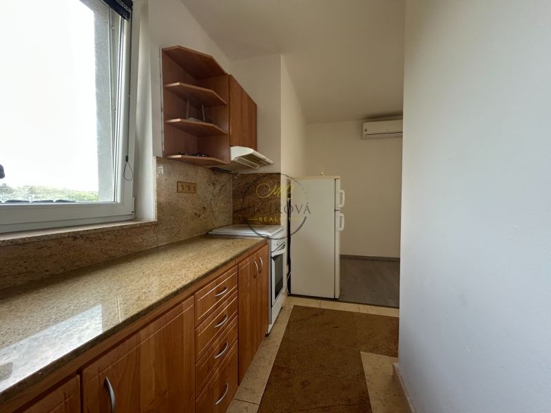 A kitchen in a 2-room apartment with a stone countertop and a window.