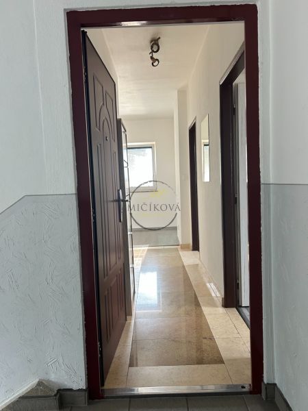 A hallway with doors and a stone floor in a 2-room apartment.