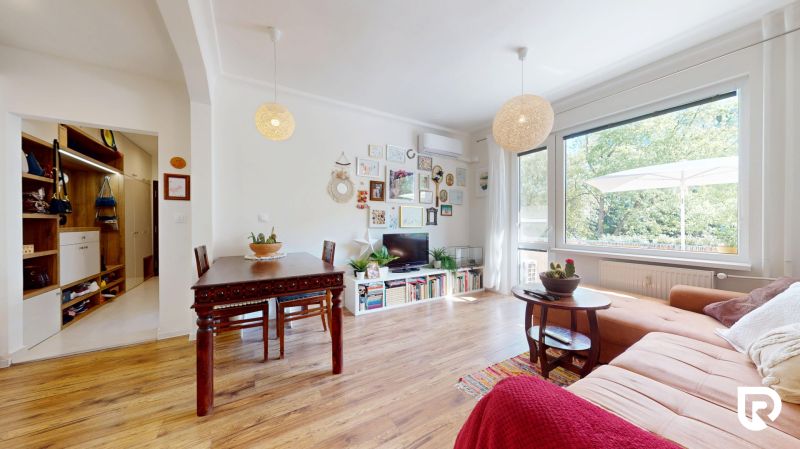 Living room in a 3-room apartment with a wooden decor floor, large window, and decorative elements.