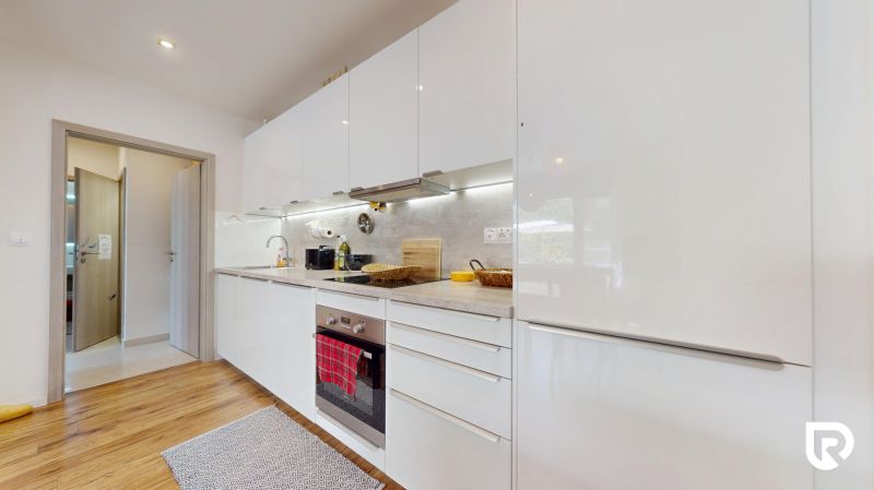 A kitchen with appliances, white cabinets, and a wood-patterned floor in a 3-room apartment.