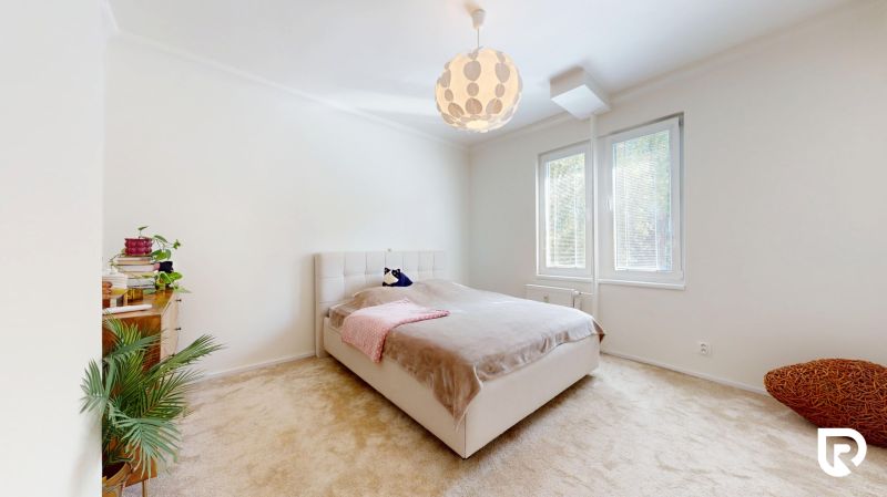 A bright bedroom with a bed, carpeted floor, and a window in a 3-room apartment.