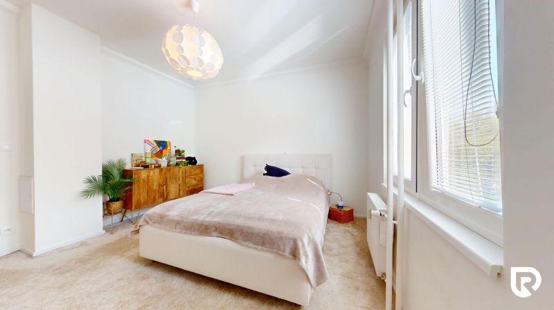 A bright bedroom with a bed, a cabinet, and a window in a 3-room apartment.