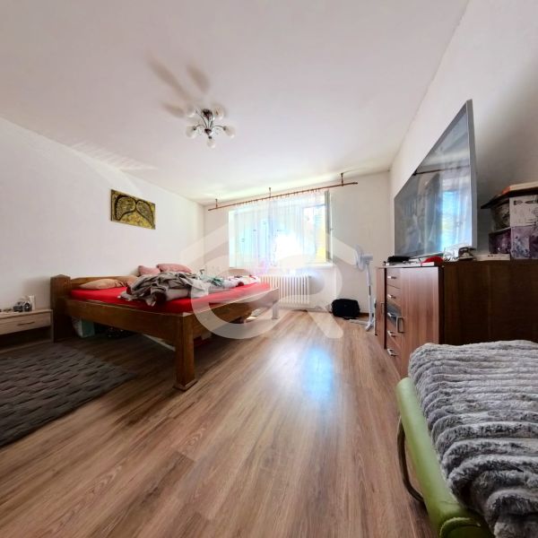 Bedroom in a family house with a bed, wardrobe, and wooden decor flooring.