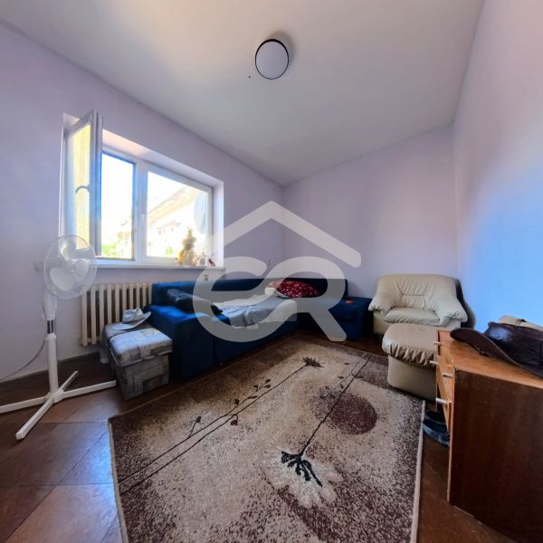 Living room in a family house with a blue sofa, an armchair, and a carpet on a floor with a wooden decor.