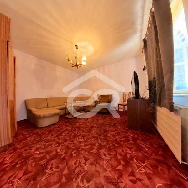 Living room in a family house with a corner sofa and a burgundy carpet.