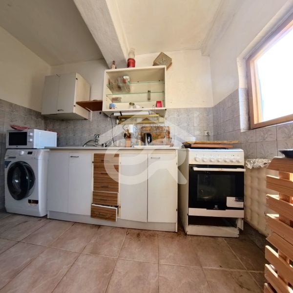 A kitchen in a family house with a ceramic floor, cabinets, a stove, a microwave, and a washing machine.