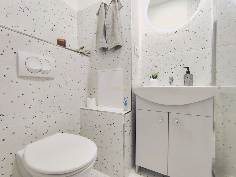 Bathroom in a 2-room apartment with terrazzo tiles, a sink, and a mirror.