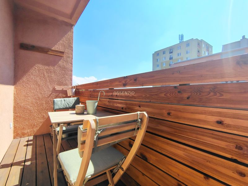 A balcony with wooden paneling and furniture in a 2-room apartment.