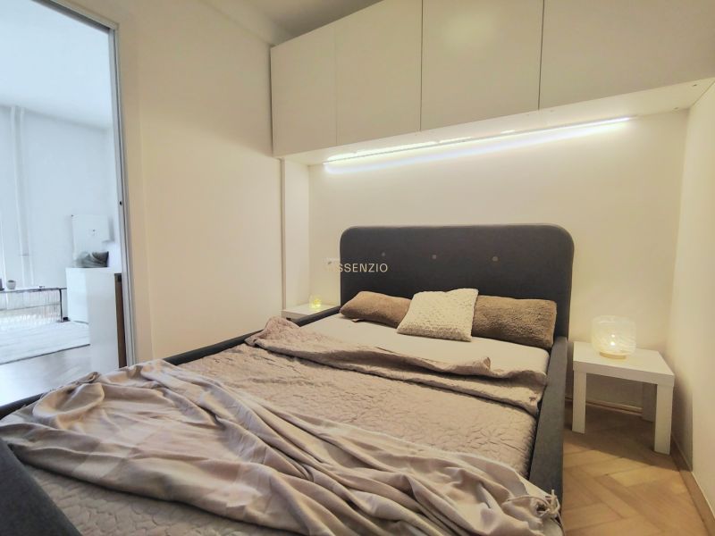 Bedroom with a bed, nightstand, and storage cabinets in a 2-room apartment.