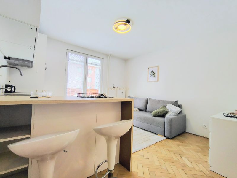 Living room in a two-room apartment with a wood-patterned floor and modern furnishings.