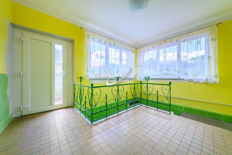 Yellow walls, green metal railing, tiled floor, bright space in a family house.