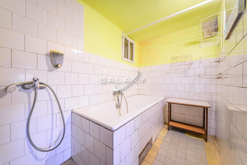 A bathroom with a bathtub and white tiles in a family house.