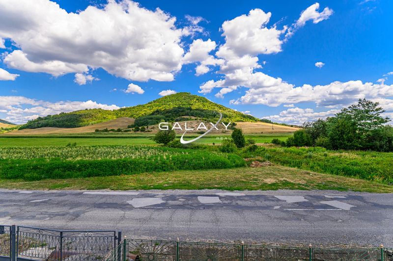 The landscape near a family house in Hajnáčka, meadows and hills under a blue sky.