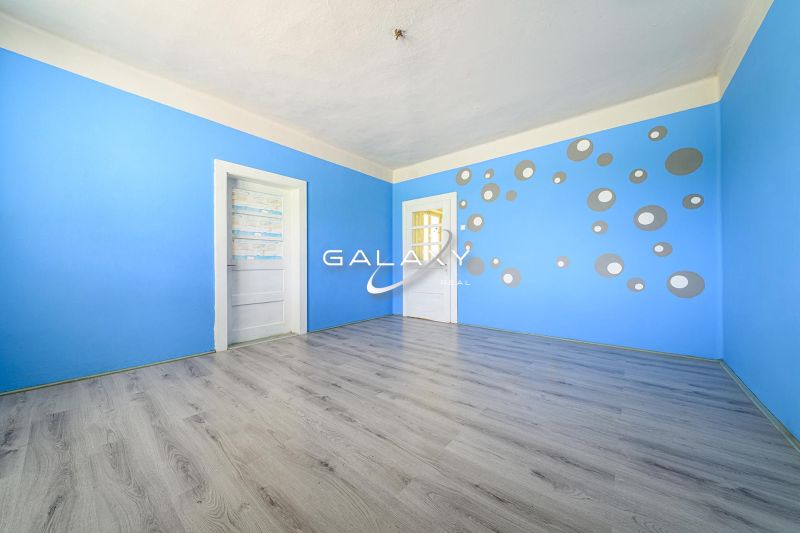 A room in a family house with blue walls, a pattern of circles, and a floor with a wooden decor.