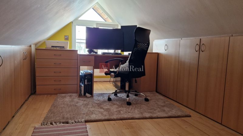 Attic office in a 2-room apartment with a wooden decor floor and a desk.