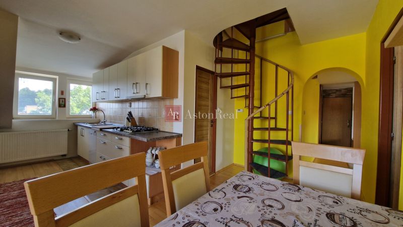 A kitchen in a 2-room apartment with a spiral staircase and light cabinets.