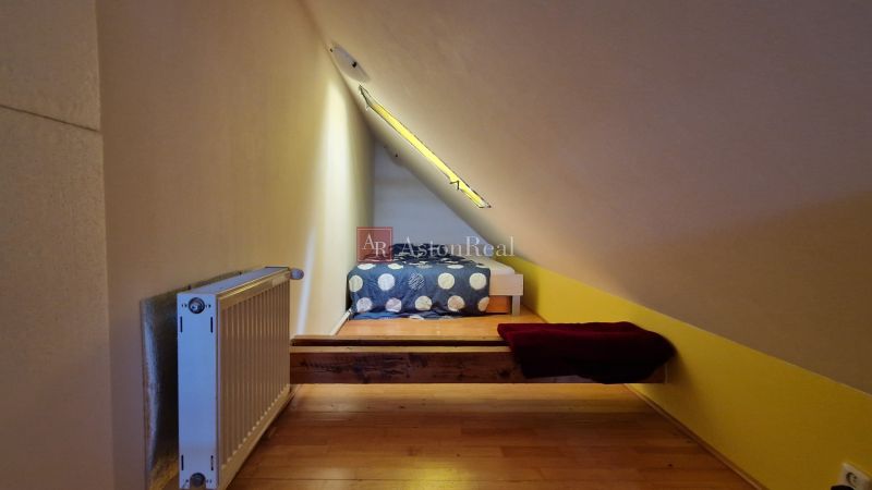Attic room with a sloped ceiling, radiator, and floor with wooden decor.