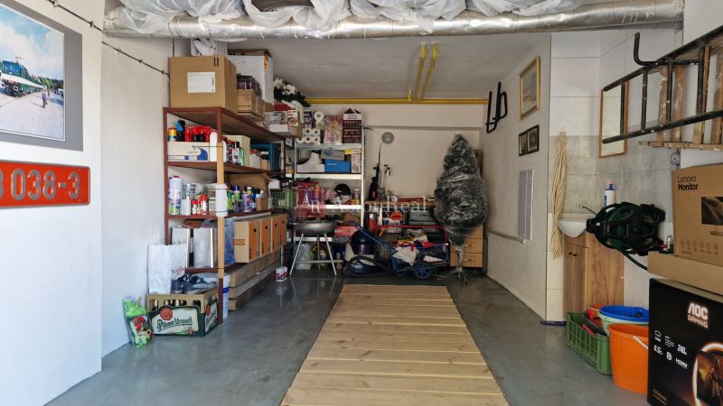 A garage full of stored items and a shelving system, next to a sink and a ladder.