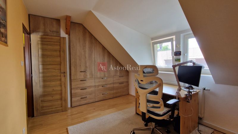 An attic space with wooden decor, a desk, and a chair in a 2-room apartment.
